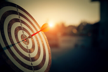 bullseye target or dart board has red dart arrow throw hitting the center of a shooting for...