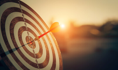 bullseye target or dart board has red dart arrow throw hitting the center of a shooting for...
