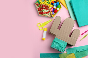 Cardboard cactus and materials on pink background, flat lay with space for text. Pinata DIY © New Africa