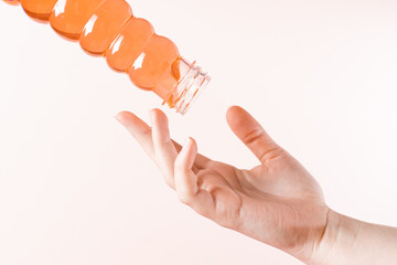 Toy children's slime from a jar flows on the girl's fingers. Wax for depilation in a jar. Light beige monochrome background