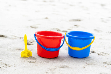 Fototapeta na wymiar Children's beach toys - buckets, spade and shovel on sand on a sunny day