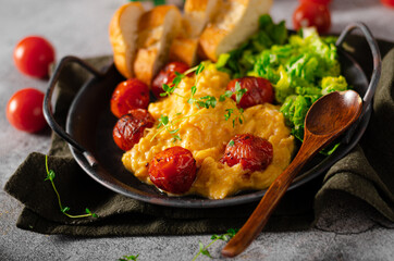 Scrambled eggs with salad and grilled tomatoes