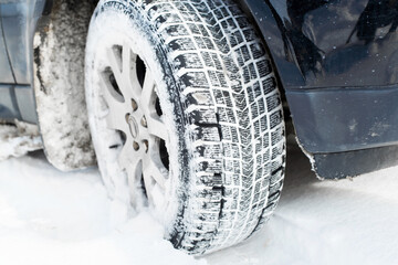 Snow-covered car wheel protector. SUV tire in a snowdrift, close-up.