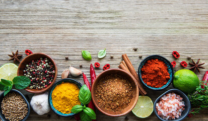 A selection of various colorful spices on a wooden table in bowls