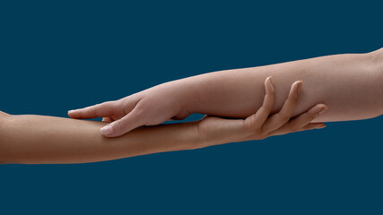 Fototapeta na wymiar Close up of two women holding each other arm isolated on blue background