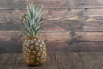 Photo of ripe juicy pineapple placed on wooden background