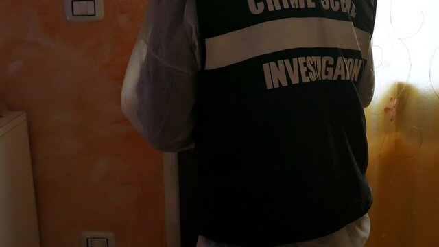 csi investigator at the crime scene who inspects with blue flashlights and takes scientific evidence to take to the laboratory taken from the handle of a house door where a murder was committed