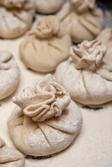 Handmade khinkali are laid out on a cutting board and sprinkled with flour. Delicious homemade food. Close-up