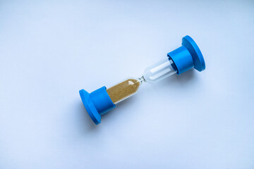 A glass hourglass rests on a white isolate