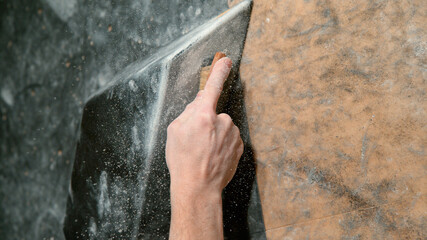 CLOSE UP: Climber uses a brush to scrub chalk powder off a black volume hold.