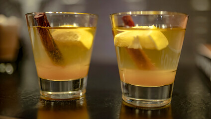 Two cocktails of whiskey, rum, lemon or brandy with cinnamon on the bar