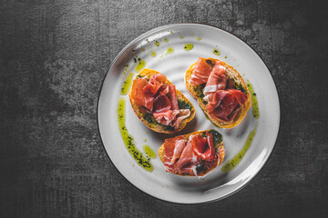 Bruschetta with prosciutto and pesto sauce on plate