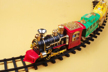 Toy steam locomotive with carriages on a yellow background. Transport symbol.