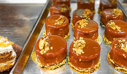 Circle brown glossy cakes with nuts on metal sheets
