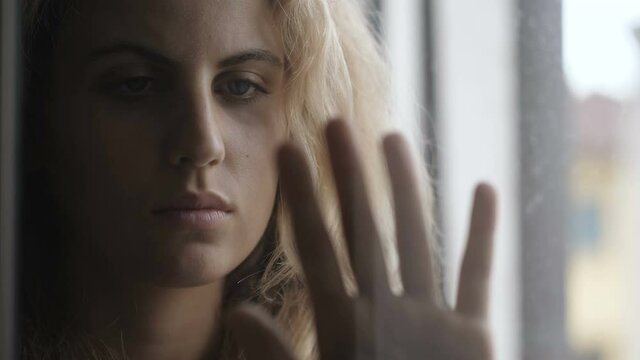restriction symbol - girl puts her hand on the window pane and stares at it