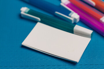 multicolored pencils and markers business cards close-up blue background