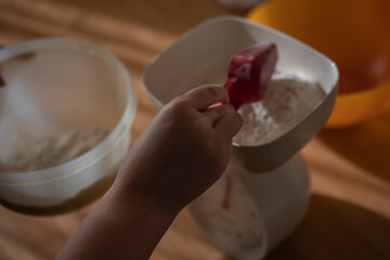 Feminine hands weighting flour on a anolog scale