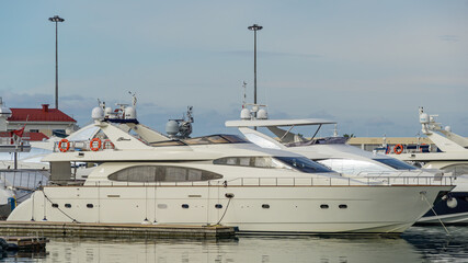 Ships, yachts and boats on blue surface of Black Sea by pier of Commercial seaport of Sochi. Resort city center. Sochi, Russia - November 23, 2020