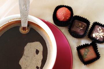 cup of dark morning coffee and chocolate candies