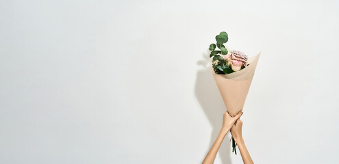 Happy Womens day. Female hands holding beautiful flowers bouquet wrapped in craft paper over light background