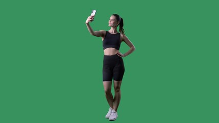 Healthy fitness young woman taking selfie photos with cell phone. Full body length on green screen chroma key. 