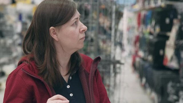Woman in store makes contactless purchase goods. She introduce product code into electronic validator, in order to picks purchases up electronic self service terminal. Consumer service automation
