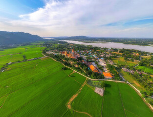 Beautiful scenery of Kanchanaburi province in Thailand. Green rice fields with city view along Mae Klong river.