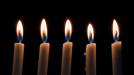 White Candles Burning in the Dark with lights glow. The burning candle's flame in the dark background. a symbol of the Christian faith. Candles Burning in the Dark with lights glow.White Candles