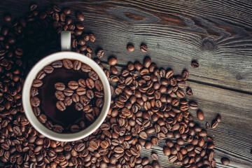 cup with aromatic drink and coffee beans on wooden background top view