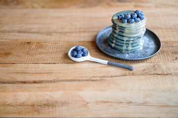 Blue american pancakes decorated with blueberry and caramel souse on vintage plate on wood table. Homemade tasty food. Celebration of Shrovetide.