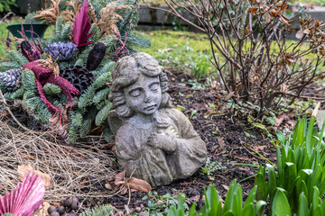 Betender Engel vor einem Korb mit Herbstschmuck