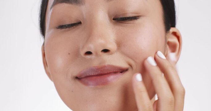 Face lifting massage. Young asian woman massaging her face for lymphatic drainage effect, white studio background