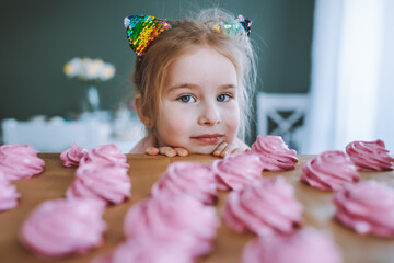 Little girl with blonde hair and blue eyes look on delicious homemade pink marshmallows ot zephyr...