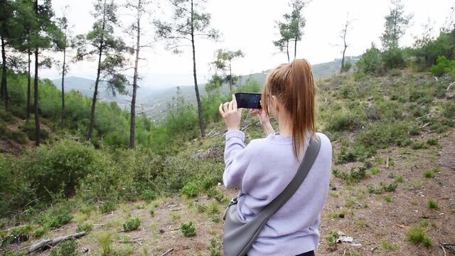 Woman taking pictures of scenic landscape at the mountain.