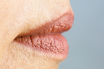 Obraz premium Lipstick painted female lips on a gray background. Close-up.