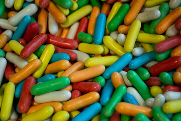 Lots of colorful candy drops in the form of capsules. Sweet bright background