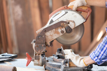 closeup hand's carpenter using electric circular saw for cutting wooden boards, on a piece of wood in workshop