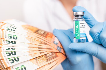 SARS - CoV2 Vaccination concept. Close up COVID-19 vaccine dose. A doctor or nurse in a laboratory holds a vial with a vaccine. Pandemic immunity. Money for the vaccine.