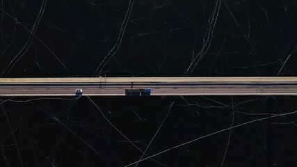 Top down view of a highway bridge spanning over a frozen lake or river on a cold sunny winters day. High quality photo © henjon