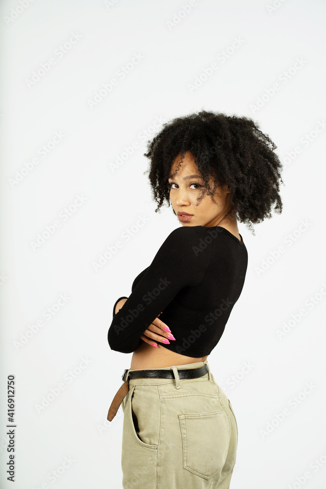 Wall mural a woman of afro appearance poses in a photo studio on a white background. looking at the camera, she