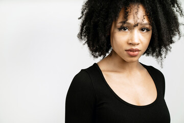 portrait of a confident Afro-looking woman posing in a photo studio on a white background. close up, a curly-haired brunette in a black short jacket is standing with her back to him. copy space.
