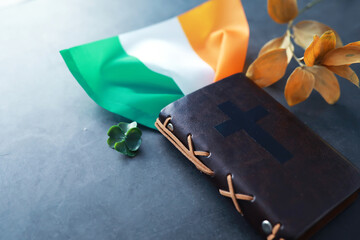 A leather-bound Bible on the table. Religious Christian Irish celebration. Four-leaf clover symbol...