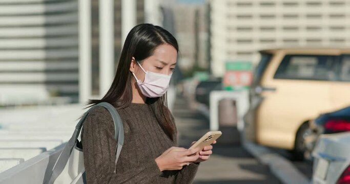 Woman wear face mask and use of smart phone to check her car on parking lot