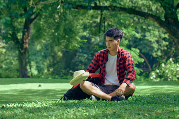 A young man sitting on the lawn at the park