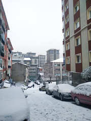 vertical view of a small street and cars covered by snow in winter time after heavy snowfall