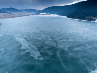 Artificial lake on a cloudy winter day, water dam for the population, focus on the ice.