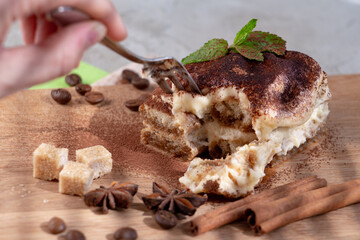 eating process a piece of delicious tiramisu, perfect dessert. Star anise and cane sugar complete the composition