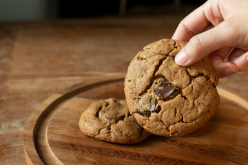 Delicious Chocolate Chip Cookies on wooden plate on wooden table. Fresh baked chocolate chip cookies on rustic wooden table. Homemade Chocolate Chip with milk glass on the background.
