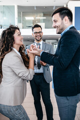 Middle age couple choosing and buying car at car showroom. Car salesman helps them to make right decision.