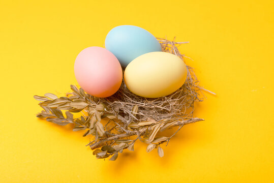 Close up photo of birds nest easter eggs over yellow background.